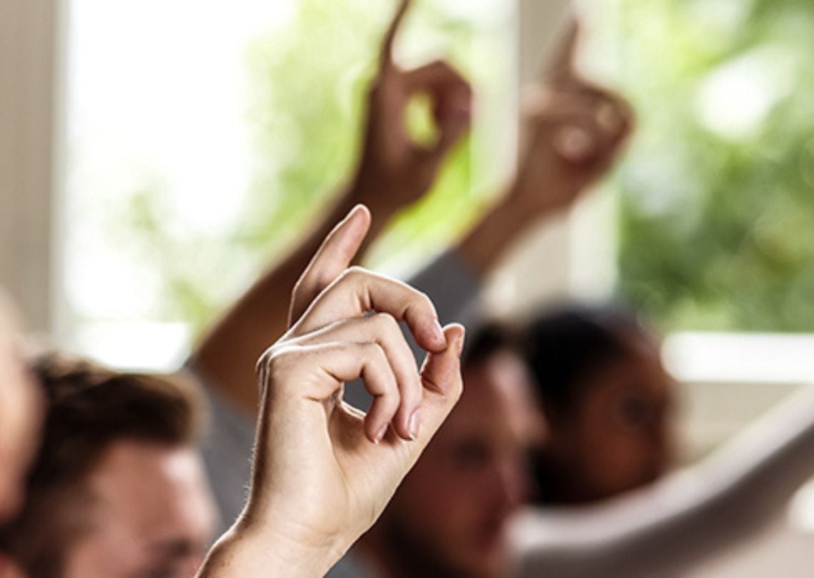 Imagem de várias mãos levantadas, simbolizando participação e interação em um ambiente de aprendizado ou discussão. Essa imagem pode representar momentos de pergunta e resposta em um evento ou aula.
