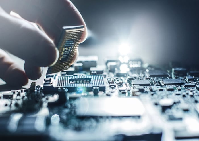 Pessoa instalando um processador de computador na placa-mãe, componentes eletrônicos visíveis em close-up, tecnologia avançada e eletrônica.