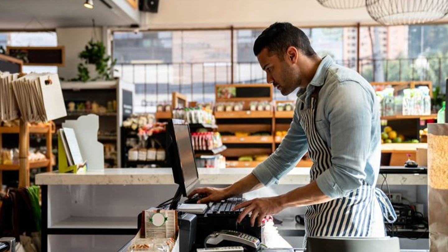 Atendente em varejo usando soluções da Glory para automação e gestão, melhorando a experiência do cliente e eficiência da equipe, representando o Flooid, comércio unificado. 