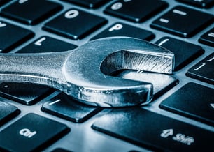 Imagem de uma chave inglesa sobre um teclado de computador, simbolizando a manutenção e reparos em dispositivos tecnológicos.
