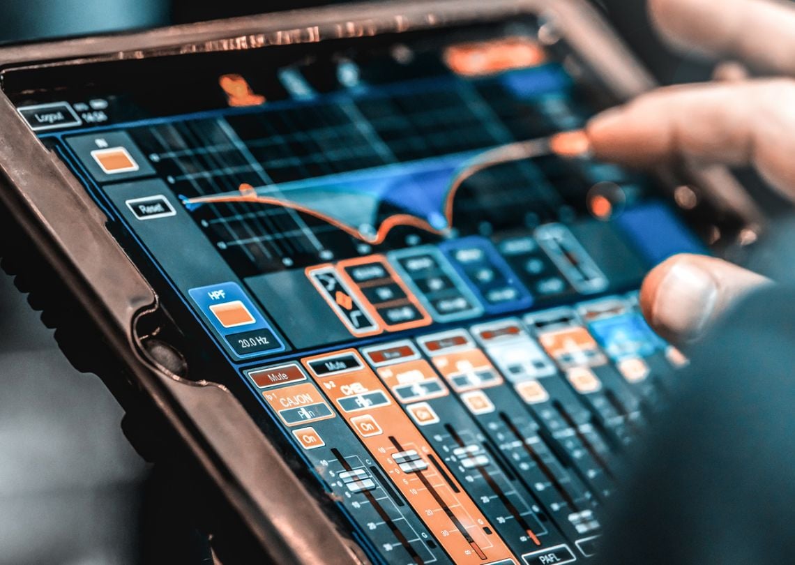 Pessoa usando dispositivo com tela sensível ao toque controlando um software de mixagem de áudio digital.