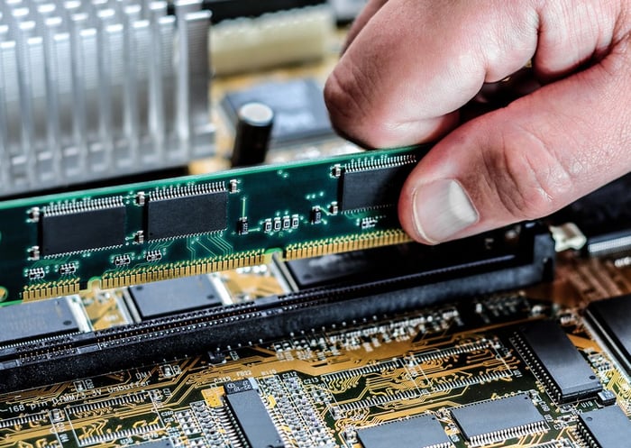 Pessoa trocando memória RAM em computador de alta performance, componente de hardware técnico, foco em tecnologia e upgrades de computadores.