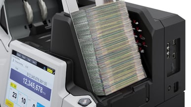 Imagem de uma máquina contadora de dinheiro, com notas de cem dólares sendo contadas. A cena mostra a importância da tecnologia na contagem precisa de dinheiro.