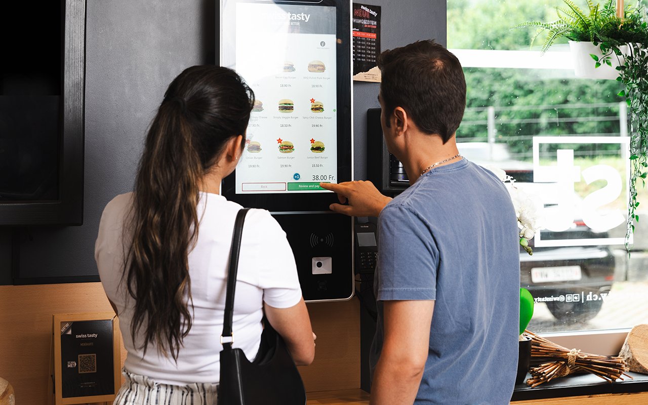 Kunden nutzen einen Selbstbestellkiosk im Restaurant