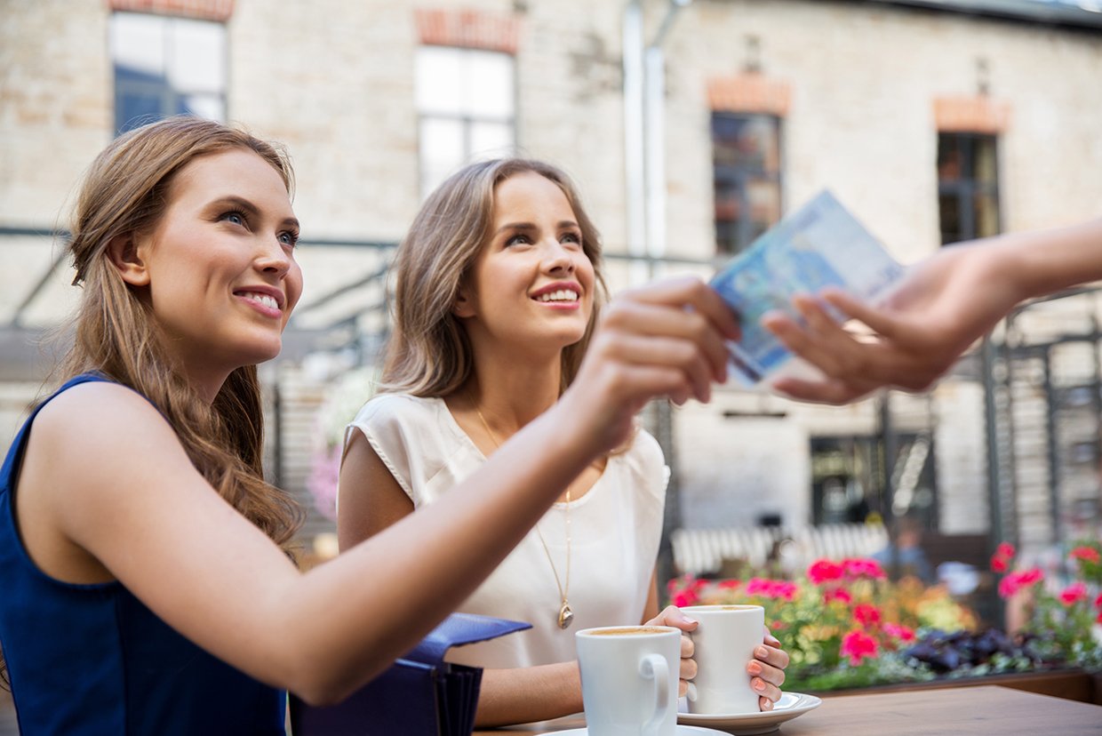 Zwei Frauen zahlen bar im Außencafé