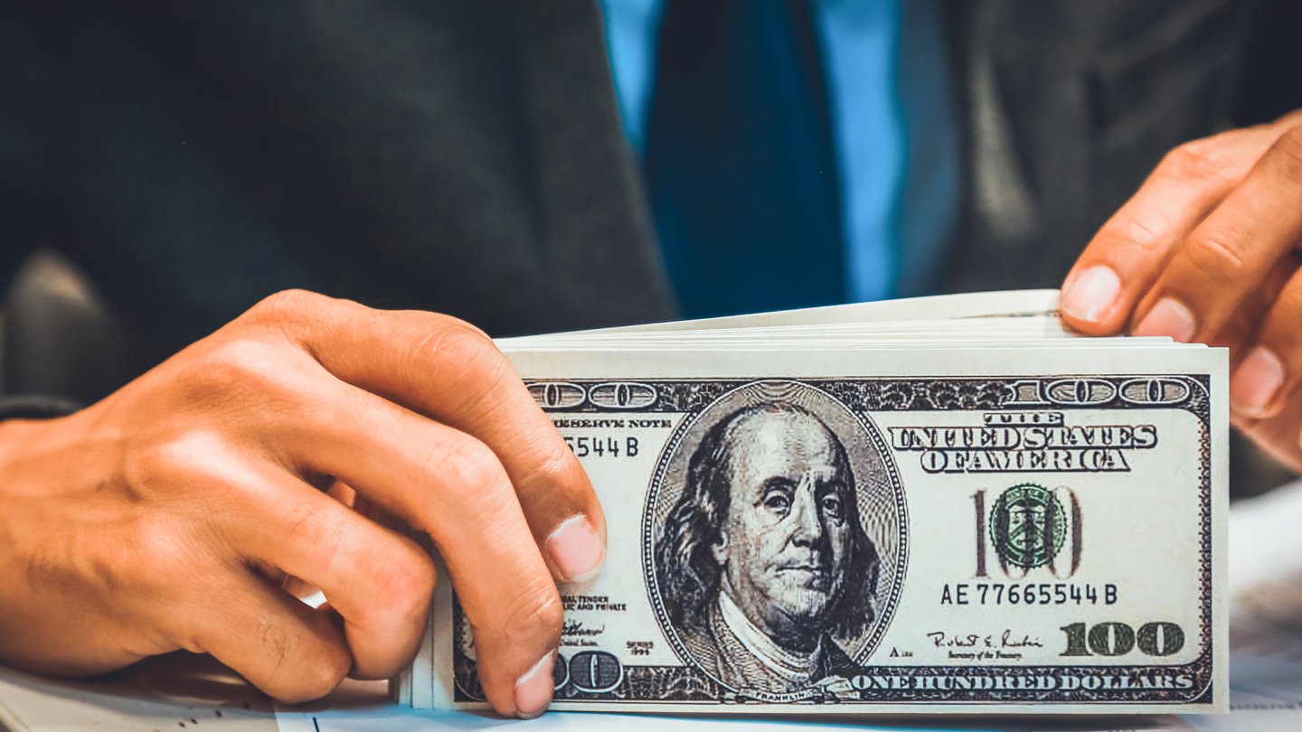 hand-holding-USD-banknotes-1140x810