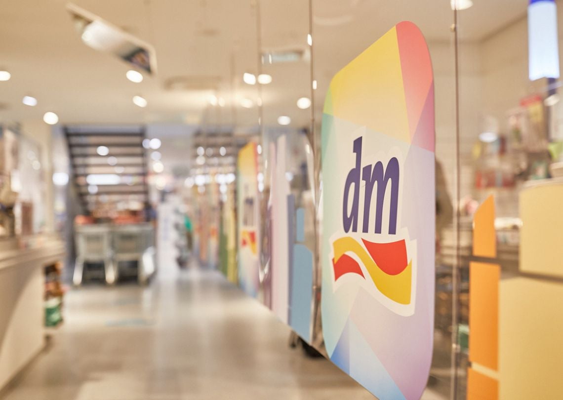 Imagem do interior da loja dm, mostrando prateleiras e uma decoração colorida que destaca a marca dm, ideal para compras de produtos de beleza e saúde.